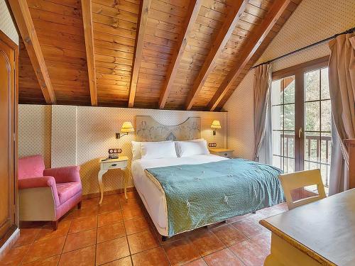 ein Schlafzimmer mit einem großen Bett und einem rosa Stuhl in der Unterkunft Hotel Bocalé 3000 in Sallent de Gállego