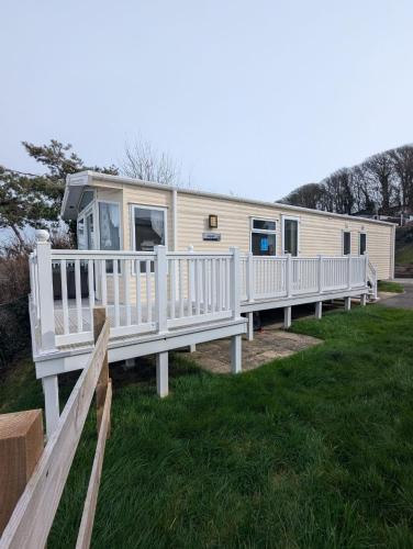 a mobile home with a porch and white railing at BEAUTIFUL LUXURY Caravan HAVEN LITTLESEA STUNNING VIEWS Sleeps 6 in Weymouth