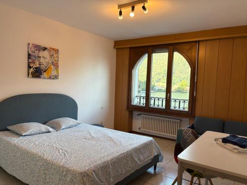 a bedroom with a bed and a table and a window at the Lake View apartment in Mendrisio