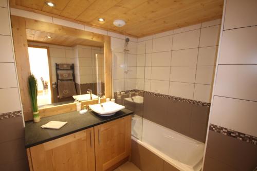 een badkamer met een wastafel, een bad en een spiegel bij Les Saisies Bisanne in Les Saisies