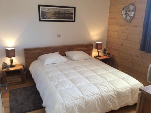 a bedroom with a large white bed with two lamps at Les Saisies Bisanne in Les Saisies