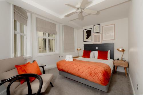 a bedroom with a bed with orange pillows and a fan at Kensington House Hotel in London