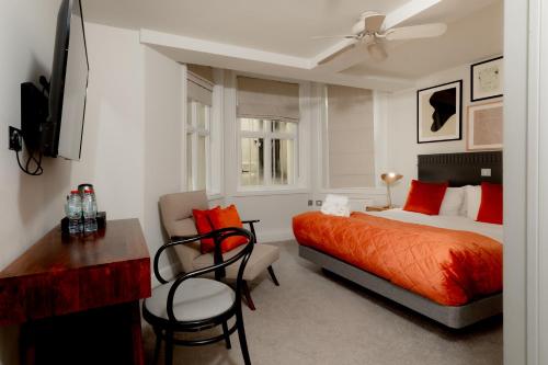 a bedroom with a bed and a table and chairs at Kensington House Hotel in London