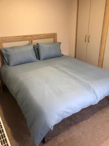 a large bed with two blue pillows on it at Dunes Escape in Lossiemouth