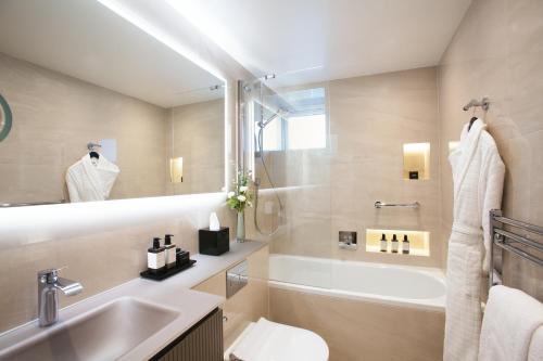 a bathroom with a sink and a tub and a toilet at The Rathbone Hotel, Fitzrovia in London