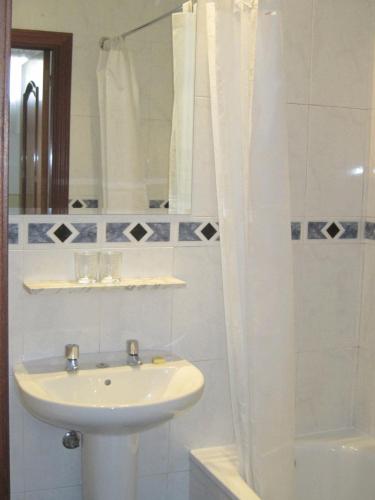 a white bathroom with a sink and a shower at Hostal Gonzalo in Madrid