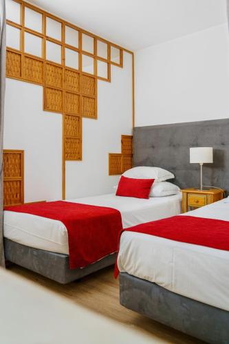 a bedroom with two beds with red and white sheets at Luna Hotel da Oura in Albufeira