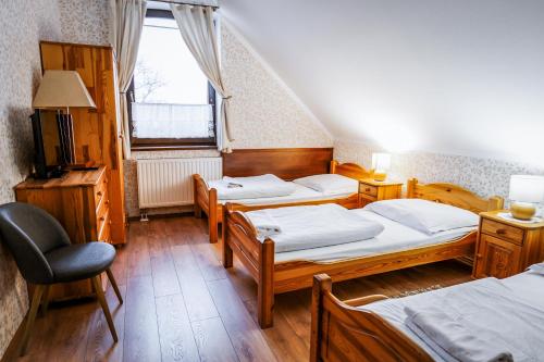 a room with three beds and a chair and a window at Dworek Galicyjski in Oświęcim