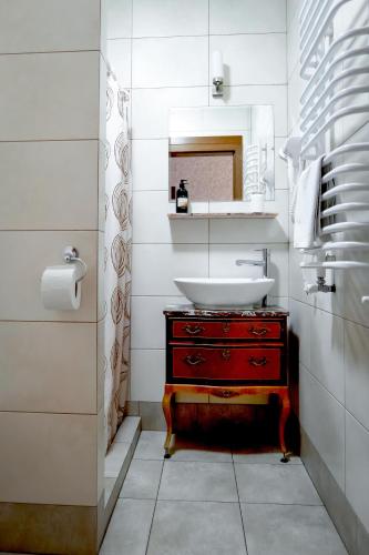 a bathroom with a sink and a red dresser at Dworek Galicyjski in Oświęcim