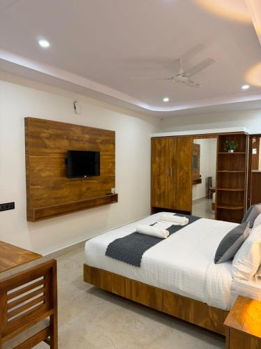 a bedroom with a large bed and a flat screen tv at HOTEL FORTUNER Inn in Bangalore