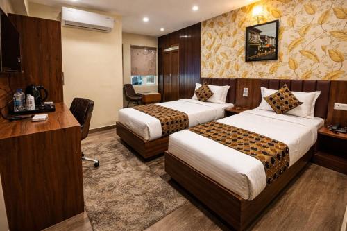 a hotel room with two beds and a desk at Hotel Downtown in Jamshedpur