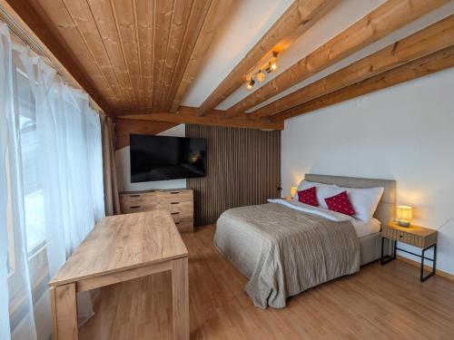 a bedroom with a bed and a flat screen tv at PlanB Stay in Samedan