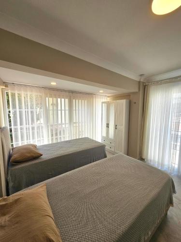 two beds in a bedroom with windows and two bedsvisor at Luxury 5BR Villa w Pool & Beach Access Ayvalık in Ayvalık