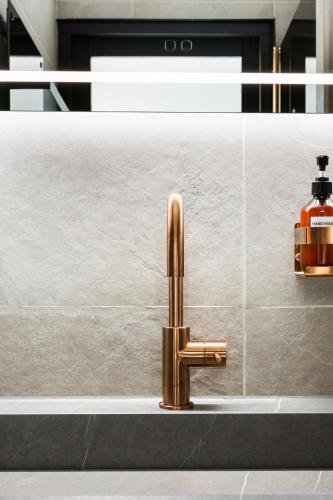 a sink with a gold faucet next to a wall at Horizon Suite at Sea in Vlissingen