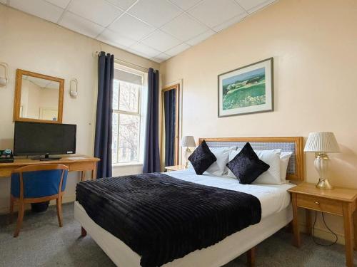a bedroom with a bed and a desk and a television at Throstles Nest Hotel in Liverpool