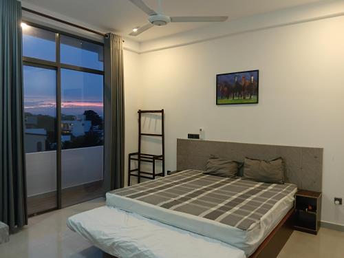 a bedroom with a bed and a large window at Sky Glow Residence in Pepiliyana