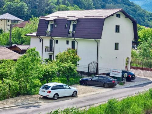 two cars parked in front of a white house at Casa TeoDora Caciulata in Căciulata