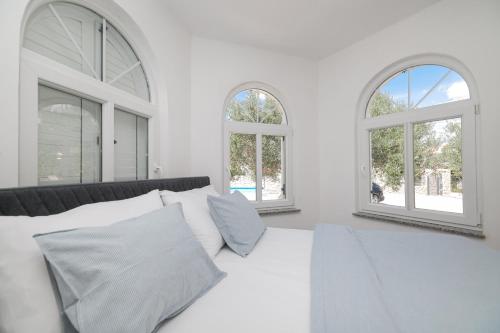 a bedroom with a white bed with two windows at Anna in Drage