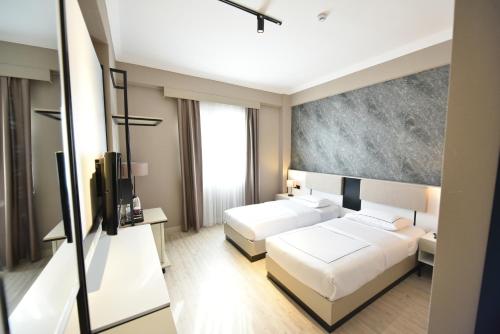 a hotel room with two beds and a television at Anemon Grand Şanlıurfa in Göktepe