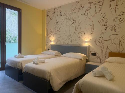 two beds in a bedroom with a mural on the wall at Hotel Piccolo Paradiso - Latronico "Terme" in Latronico