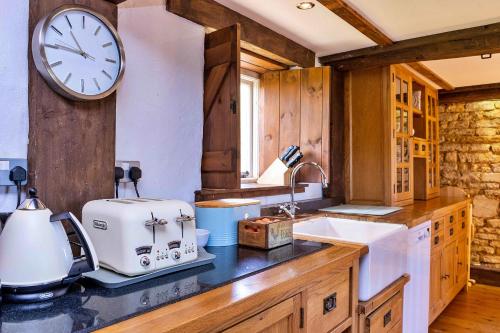 a kitchen with a counter with a clock on the wall at Finest Retreats - Fletland Mill in Stamford