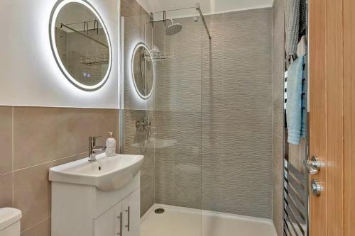 a bathroom with a sink and a shower with a mirror at Finest Retreats - The Den in Stamford