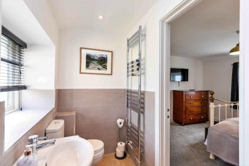 a bathroom with a sink and a toilet and a bedroom at Finest Retreats - The Warren in Stamford