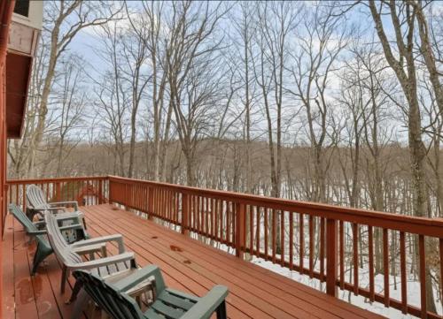 a deck with three chairs and a view of the woods at Pet-Friendly w Fire Pit Grill & Resort Access in Hedgesville