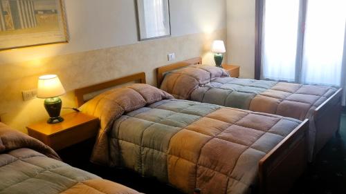 a hotel room with three beds and a lamp at Hotel Rizzi in Monticello Conte Otto