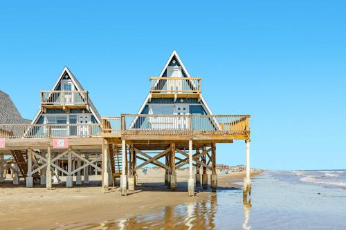 two houses on a beach with the ocean at Iconic A Frame Sleep Over the Gulf in Surfside Beach