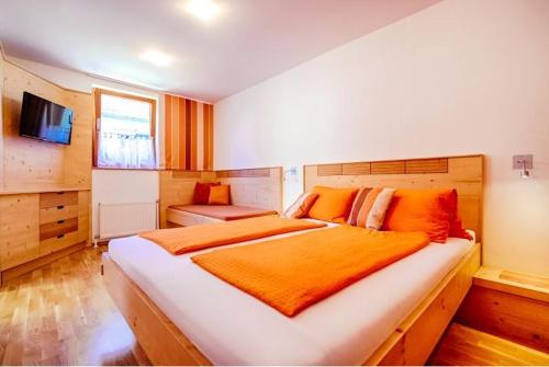 ein Schlafzimmer mit einem großen Bett mit einer orangefarbenen Decke in der Unterkunft Winzerhof Agerlhof in Jois