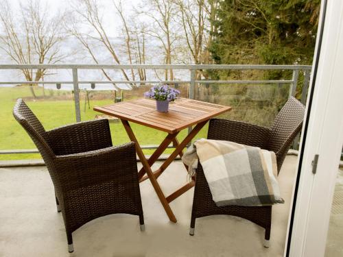 einen Holztisch und Stühle auf einem Balkon mit einem Tisch und Blumen in der Unterkunft Ferienwohnung Seeblick Plöner See in Ascheberg