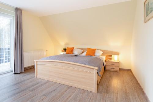 a bedroom with a large bed with orange pillows at Haus 1 Matrose in Kellenhusen