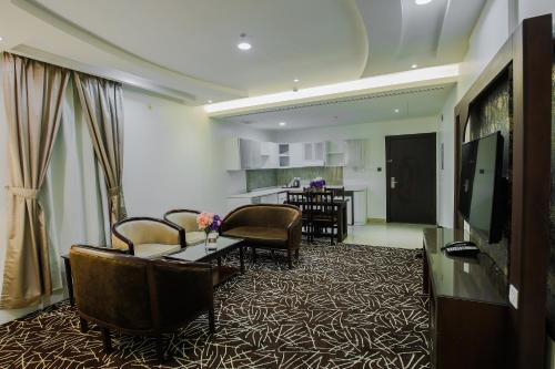 a living room with chairs and a table and a kitchen at Rest Night Serviced Apartments- AlHamra in Riyadh