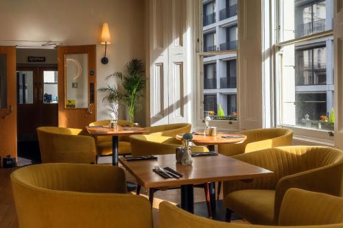 a restaurant with tables and chairs and windows at Kensington House Hotel in London