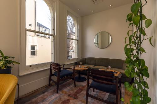 a living room with a couch and a table and chairs at Kensington House Hotel in London