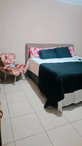 a bedroom with a bed and a chair at Sonho de verão in Guarulhos