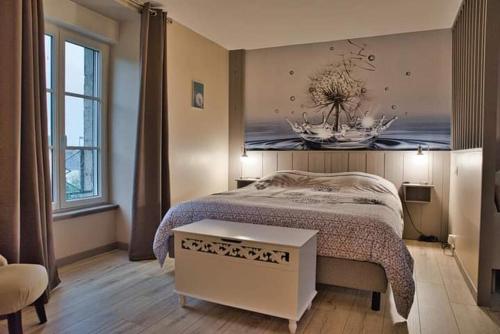a bedroom with a bed with a painting on the wall at LA Jacarandière in Le Cambout