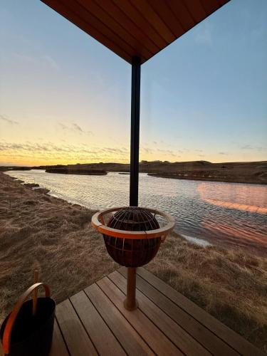 a fire pit sitting on a deck next to a body of water at Nest Retreat Iceland - Mirror Houses by the Rangá river in Hella