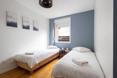 two beds in a room with a window at Gîte La perle d’Alsace in Bernardswiller