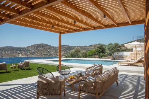 a patio with a table and chairs and a pool at Villa Consta with Tennis, Saltwater Pool & Sea Views by KB Hospitality in Dhaskalión