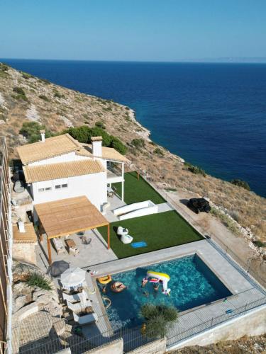 a house with a swimming pool next to the ocean at Villa Consta with Tennis, Saltwater Pool & Sea Views by KB Hospitality in Dhaskalión