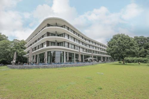a large building with a grass field in front of it at Fletcher Hotel-Restaurant de Wageningsche Berg in Wageningen