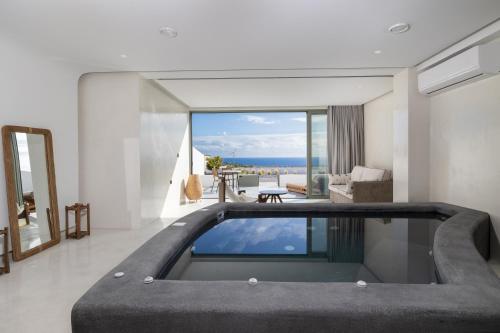 a room with a swimming pool with a view of the ocean at Acro Caldo Suites in Akrotiri