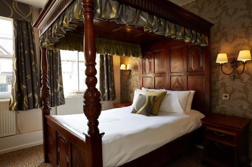 a bedroom with a canopy bed with white sheets at Ye Olde Talbot Hotel by Greene King Inns in Worcester