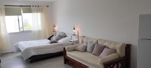 a bedroom with a bed and a couch at Ambar Estudio in Miramar