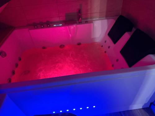 a pink bathtub with red dye in a room at Appartement jacuzzi et spa étoile Mystérieuse in Belfort