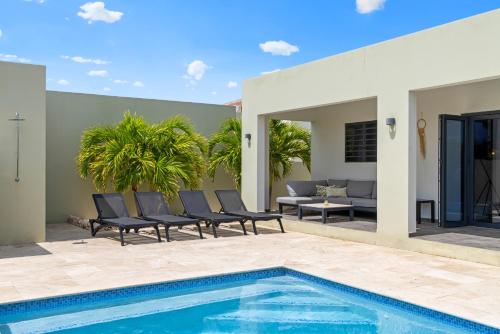 a patio with a swimming pool and chairs next to a house at Villa Jasmijn, Mambo Beach, Private Pool in Willemstad