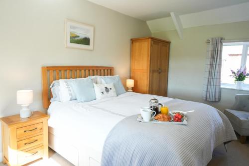 a bedroom with a bed with a tray of food on it at Honeysuckle Cottage in Hele