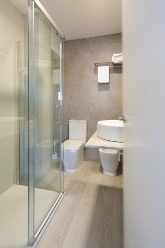 a bathroom with a toilet and a glass shower at Sol Playa Suites in Valencia